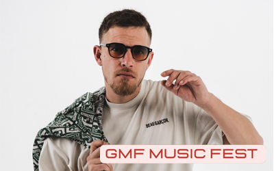 L’image montre Lil’Kev, un jeune DJ au look urbain et dynamique. Il porte une veste foncée avec des motifs clairs et adopte une pose confiante, légèrement penché en avant, les mains jointes. Son expression est sérieuse et concentrée, renforçant son image de performer professionnel. Le fond est sobre et sombre, ce qui met en valeur sa silhouette et donne un style moderne, électro et un peu mystérieux, en accord avec l’univers des soirées DJ et des musiques actuelles.